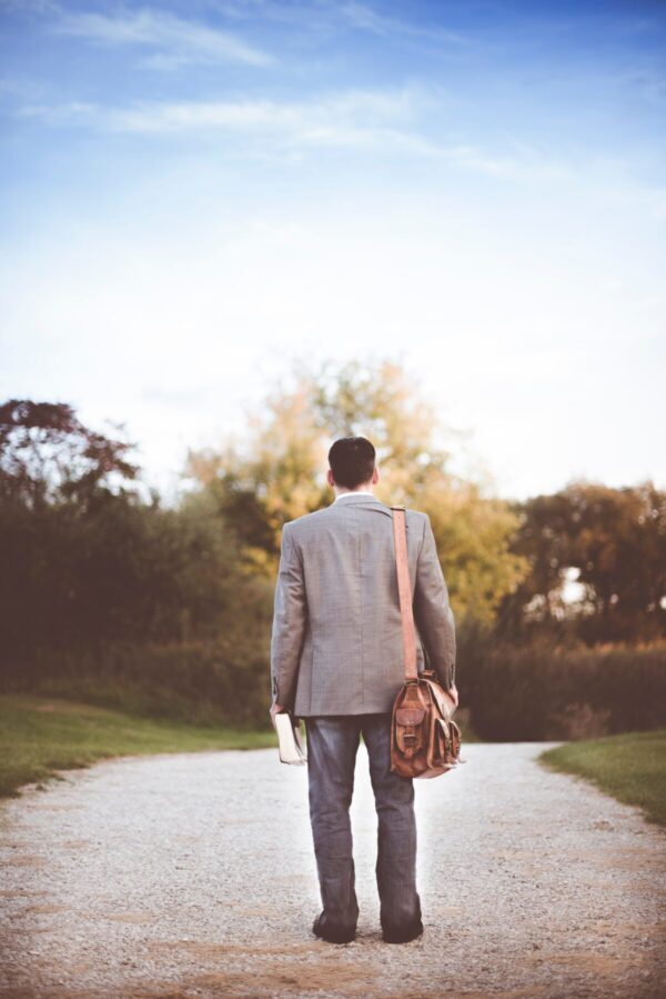 Man from behind standing with briefcase in middle of road